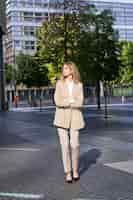 Photo gratuite portrait de jeune femme d'affaires confiante en costume beige debout dans la rue dans sa tenue d'affaires