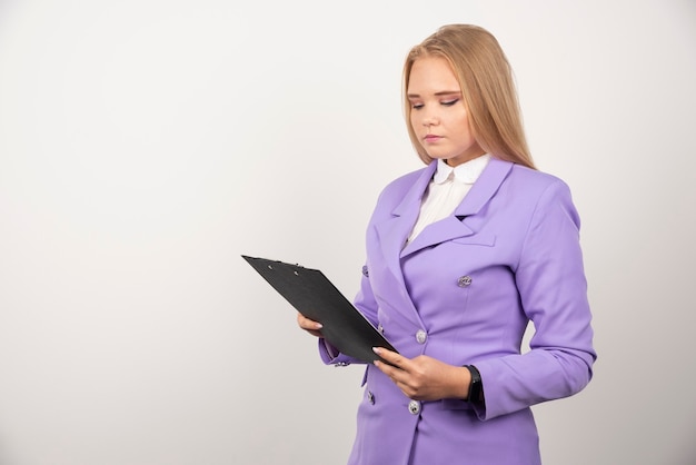 Portrait de jeune femme d'affaires debout et regardant sur le presse-papiers.