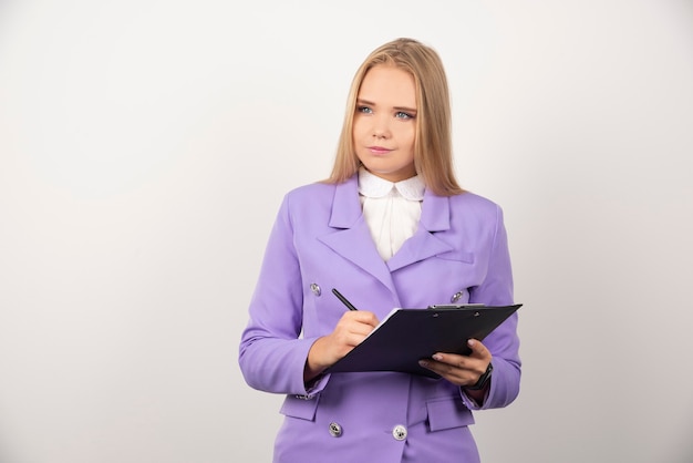 Portrait de jeune femme d'affaires debout et tenant le presse-papiers.