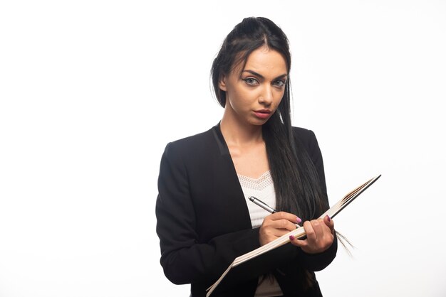 Portrait de jeune femme d'affaires écrit dans un cahier avec un stylo