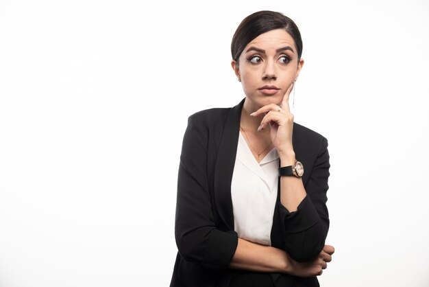 Portrait de jeune femme d'affaires posant sur un mur blanc.