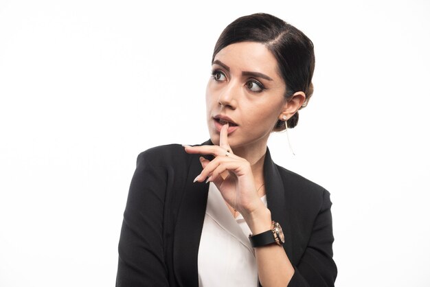 Portrait de jeune femme d'affaires posant sur un mur blanc.