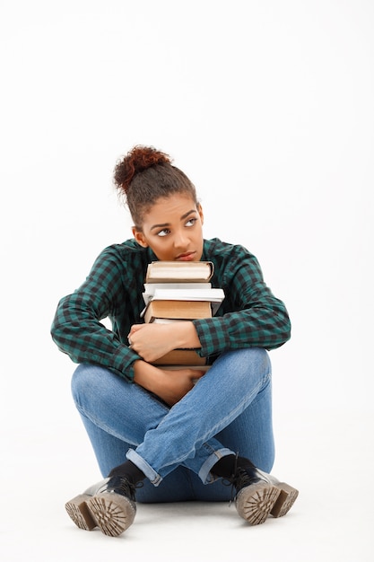 Portrait de jeune femme africaine avec des livres sur blanc.