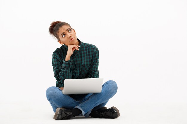 Portrait de jeune femme africaine avec ordinateur portable sur blanc