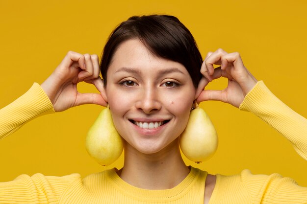 Portrait de jeune femme à l'aide de poires comme boucles d'oreilles