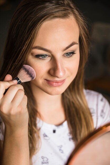 Portrait d&#39;une jeune femme appliquant le fard à joues sur son visage