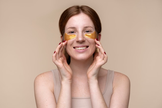 Photo gratuite portrait d'une jeune femme appliquant des patchs sous les yeux