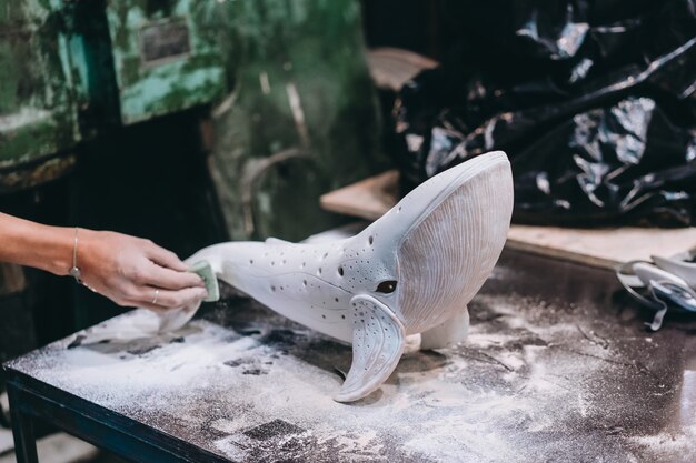 Portrait de jeune femme appréciant l'emploi préféré en atelier. Le potier travaille soigneusement sur la baleine en céramique