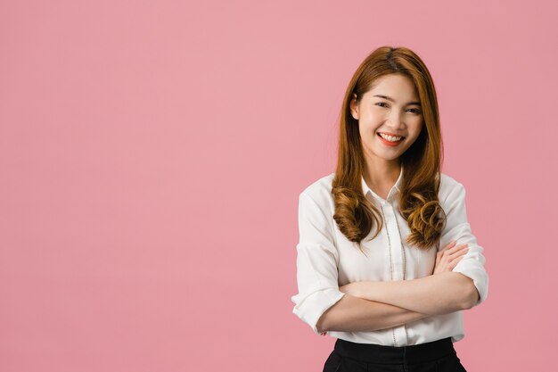 Portrait d'une jeune femme asiatique avec une expression positive, les bras croisés, un large sourire, vêtue de vêtements décontractés et regardant la caméra sur fond rose.