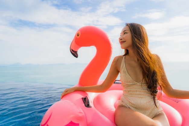 Portrait de jeune femme asiatique sur flamant flottant gonflable autour de la piscine extérieure de l'hôtel