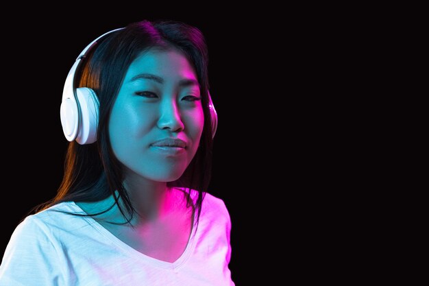 Portrait de jeune femme asiatique sur fond de studio sombre en néon Concept d'émotions humaines expression faciale annonce de vente pour les jeunes