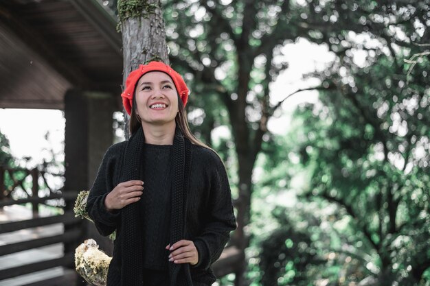 Portrait d'une jeune femme asiatique heureuse en costume d'hiver dans la forêt avec espace de copie Concept de vacances et de voyage