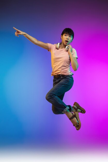 Portrait d'une jeune femme asiatique sur un mur de studio dégradé en néon