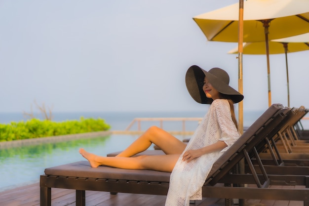 Portrait jeune femme asiatique sourire heureux se détendre autour de la piscine extérieure