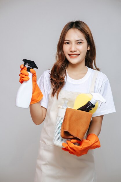 Portrait jeune femme asiatique en tablier et gants en caoutchouc, sourire et tenue de matériel de nettoyage à la main, espace pour copie
