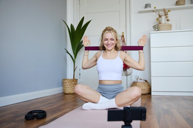 Portrait d'une jeune femme athlétique enregistrant des vidéos d'entraînement à domicile pour la remise en forme sportive