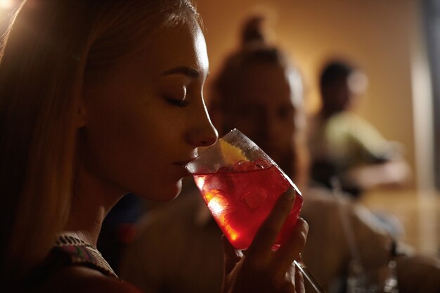 Portrait de jeune femme aux cheveux blonds tenant un cocktail