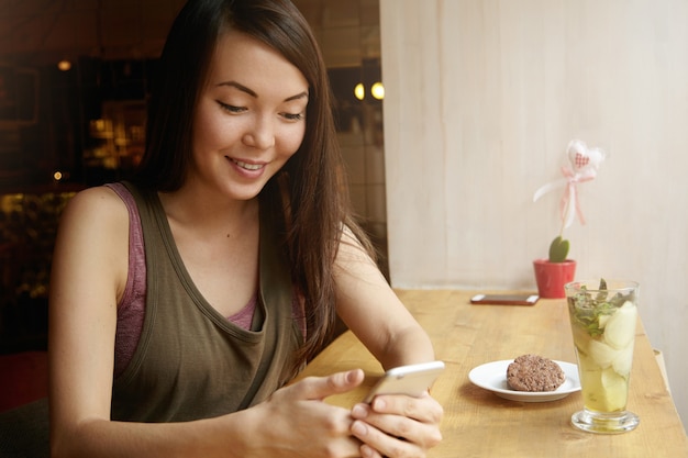 Portrait de jeune femme aux cheveux brune à l'aide de téléphone