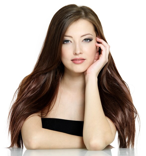 Portrait de jeune femme aux longs cheveux raides bruns sur fond blanc