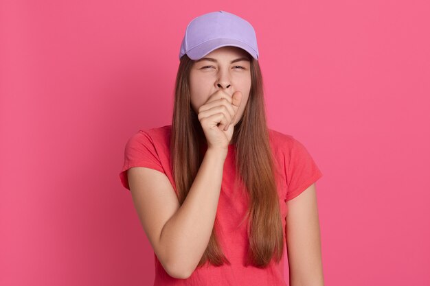 Portrait de jeune femme bâillant. Fatigué femme posant isolé sur mur rose