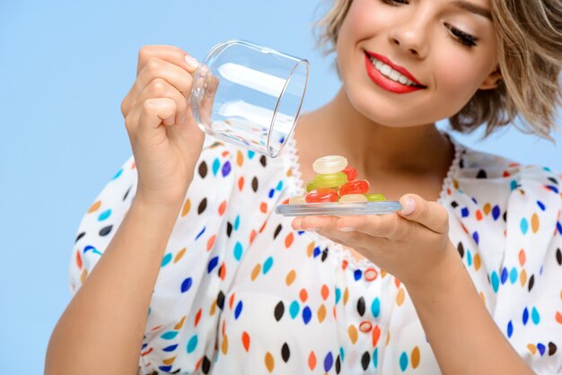 Portrait de jeune femme belle avec des bonbons sur le mur bleu