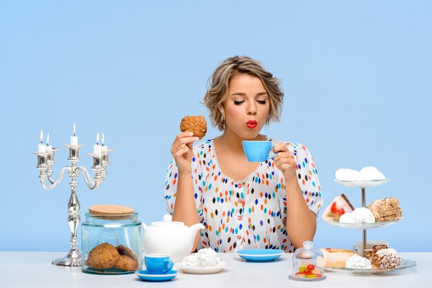 Portrait de jeune femme belle avec des bonbons sur le mur bleu