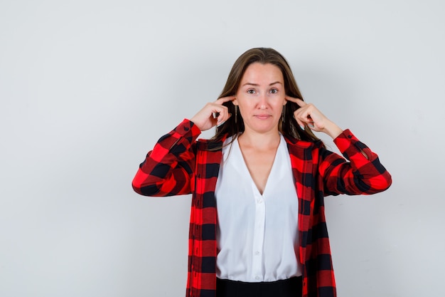 Photo gratuite portrait de jeune femme belle boucher les oreilles avec les doigts en tenue décontractée et à la vue de face triste