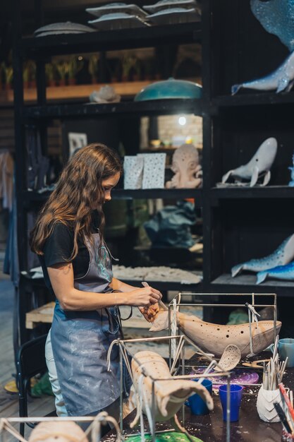 Portrait de jeune femme bénéficiant d'un travail préféré en atelier. Le potier travaille soigneusement sur la baleine d'argile