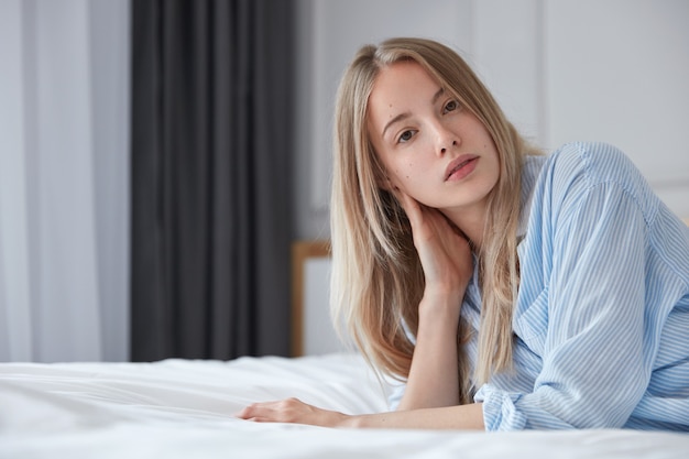 Portrait de jeune femme blonde au lit