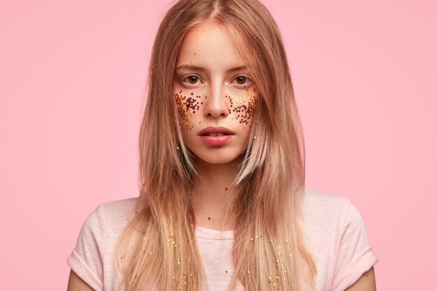 Portrait de jeune femme blonde avec des paillettes sur le visage