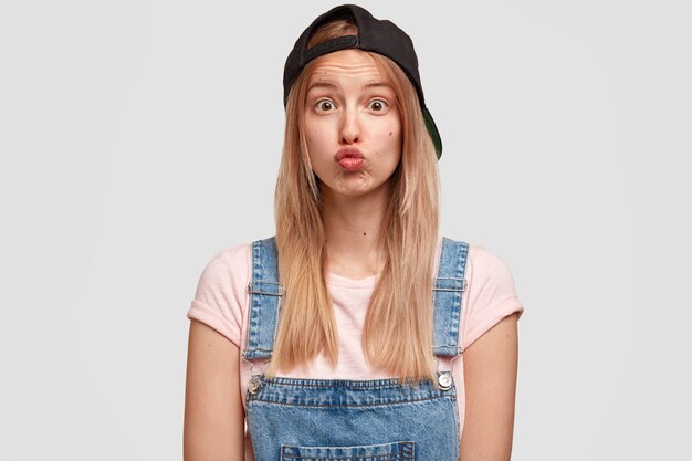 Portrait de jeune femme blonde en salopette en denim