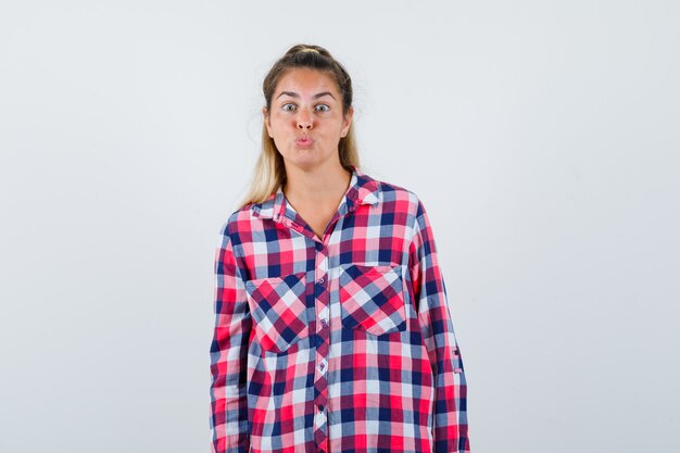 Portrait de jeune femme boudant les lèvres en chemise à carreaux et à la belle vue de face