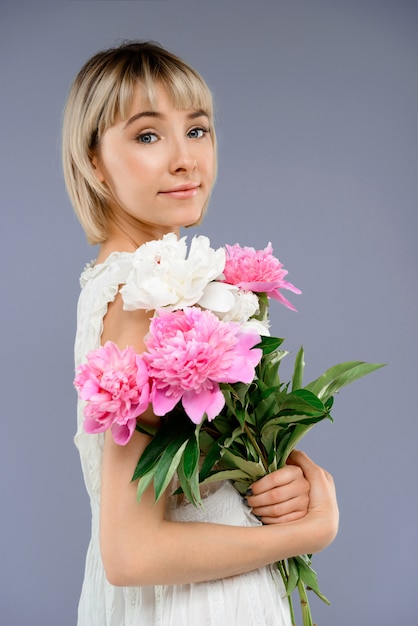 Portrait jeune femme avec bouquet de fleurs sur backgro gris