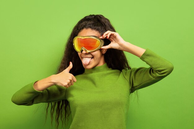 Portrait de jeune femme brune afro-américaine en masque de ski sur vert