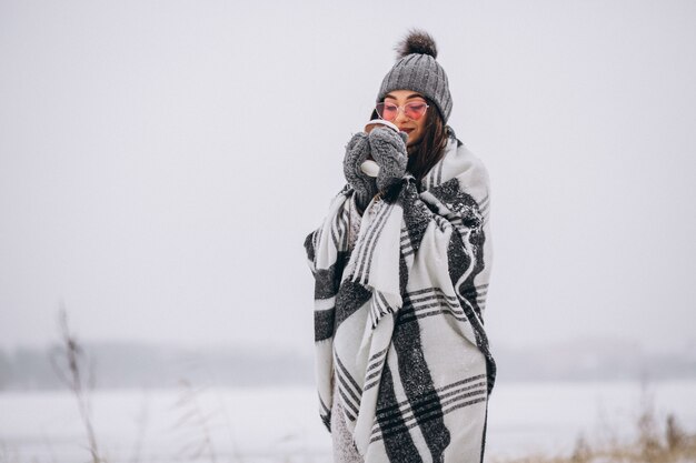 Portrait de jeune femme buvant du café dans un parc d&#39;hiver