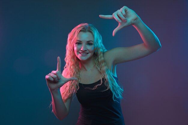 Portrait de jeune femme caucasienne sur fond dégradé en néon. Beau modèle féminin au look inhabituel. Concept d'émotions humaines, expression faciale, ventes, publicité. Sourire mignon.