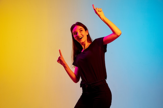 Portrait de jeune femme caucasienne sur fond de studio dégradé bleu-jaune en néon. Concept de jeunesse, émotions humaines, expression faciale, ventes, publicité. Beau modèle brune.