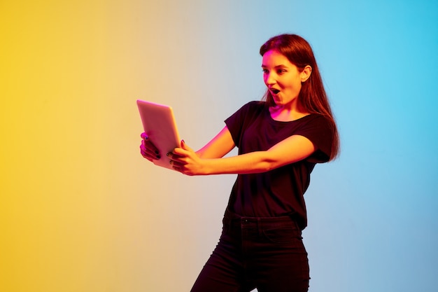 Portrait de jeune femme caucasienne sur fond de studio dégradé bleu-jaune en néon. Concept de jeunesse, émotions humaines, expression faciale, ventes, publicité. Beau modèle brune.