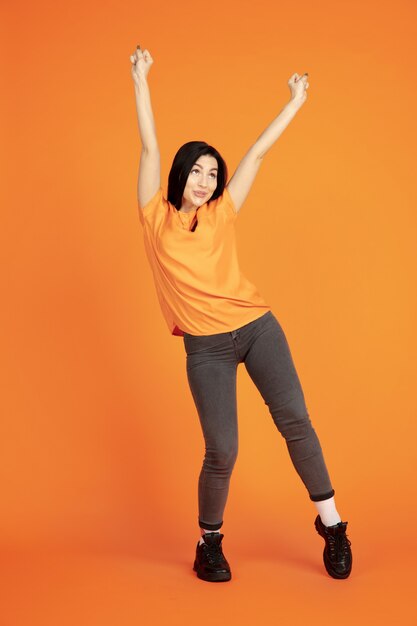 Portrait de jeune femme caucasienne sur fond de studio orange.