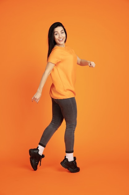 Portrait de jeune femme caucasienne sur fond de studio orange.