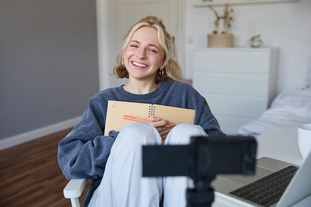 Photo gratuite portrait d'une jeune femme charismatique souriante créateur de contenu enregistre une vidéo sur une caméra numérique en riant