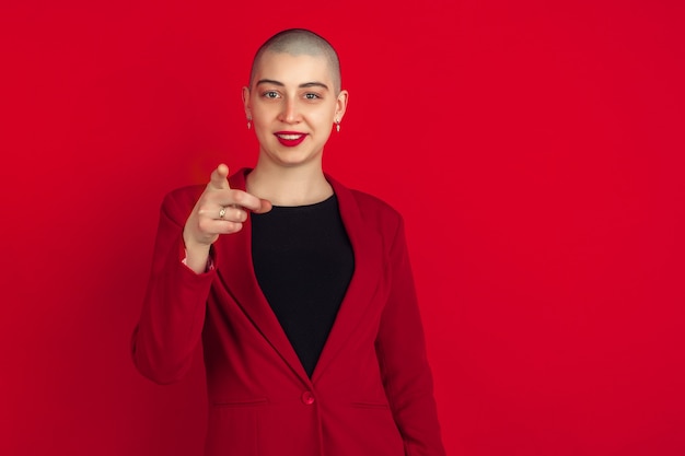 Portrait de jeune femme chauve caucasienne sur mur rouge