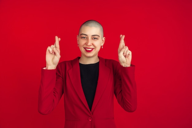 Portrait de jeune femme chauve caucasienne sur mur rouge