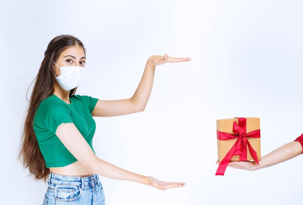 Portrait de jeune femme en chemise verte montrant une boîte-cadeau.