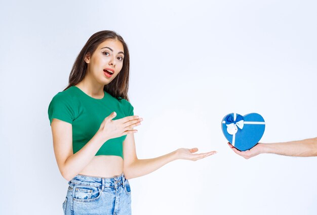 Portrait de jeune femme en chemise verte recevant une boîte cadeau bleue de quelqu'un.