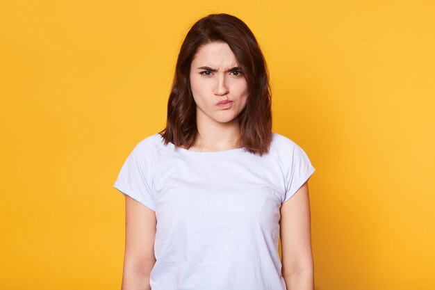 Portrait de jeune femme en colère, fronçant les sourcils sur jaune