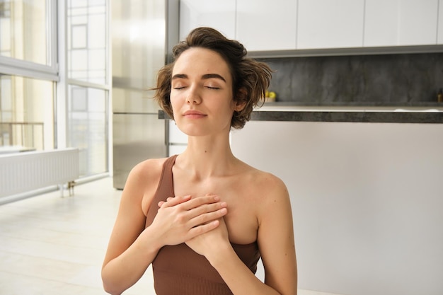 Portrait de jeune femme consciente ouvre son chakra faisant du yoga sur un tapis en caoutchouc à la maison ferme les yeux et sm