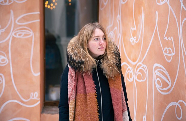 Portrait d'une jeune femme contre un mur orange avec des dessins portrait d'hiver