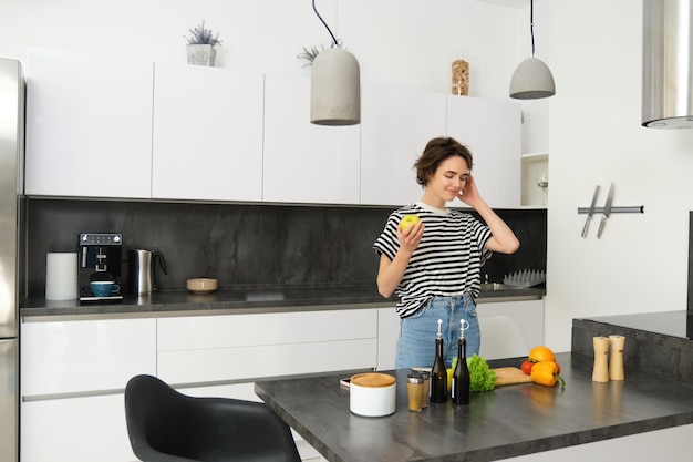 Photo gratuite portrait d'une jeune femme cuisinant de la salade une jolie fille végétalienne coupant des légumes sur le comptoir de la cuisine