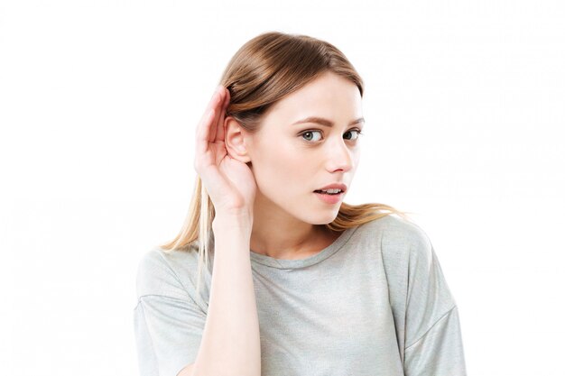 Portrait d'une jeune femme curieuse essayant d'entendre des rumeurs